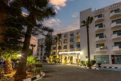 a large building with palm trees in front of it at Antigoni Hotel in Protaras
