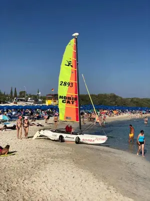 a sailboat on a beach with a crowd of people at Tsokkos Paradise Holiday Village in Ayia Napa