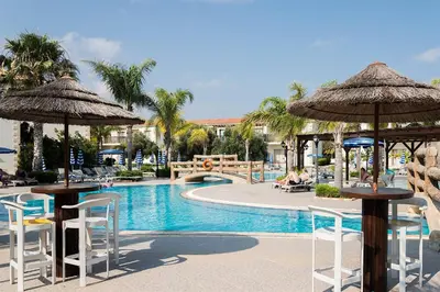 a pool at a resort with chairs and umbrellas at Tsokkos Paradise Holiday Village in Ayia Napa