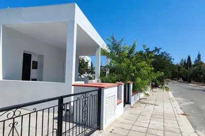 a white building with a black railing on a street at Bungalow House Kiti, seaside in Kiti