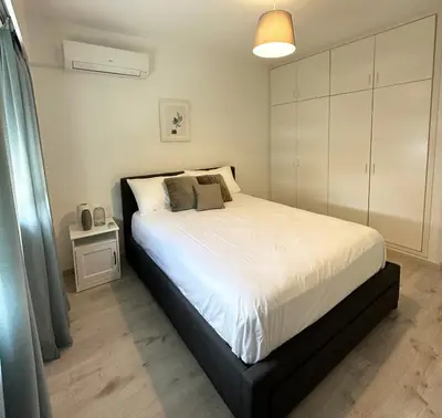 a bedroom with a large white bed with a night stand at Melia Suites in Limassol