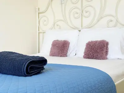 a bed with purple pillows and a blue blanket at Angela's Sunset Holiday Apt - Ayia Napa in Ayia Napa