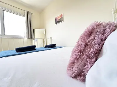 a bedroom with a large white bed with a pink blanket at Angela's Sunset Holiday Apt - Ayia Napa in Ayia Napa
