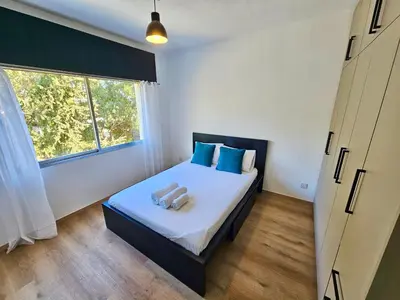 a bedroom with a bed with blue pillows and a window at Central Riverside Escape Charming 1- Bedroom Flat in Limassol
