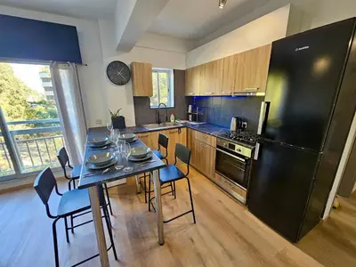 a kitchen with a table and a black refrigerator at Central Riverside Escape Charming 1- Bedroom Flat in Limassol