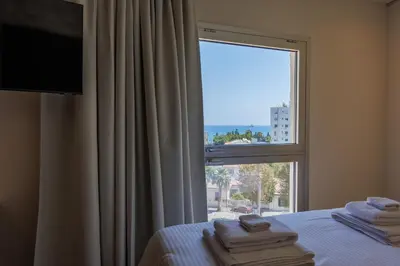 a bedroom with a large window with towels on a bed at The Palm Suites - Adults Only in Limassol
