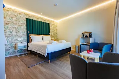 a hotel room with a bed and two chairs at The Palm Suites - Adults Only in Limassol
