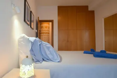 a bedroom with a bed with blue sheets and wooden cabinets at Awesome Sea & Marina View City Center 1 Bdr Flat in Larnaka