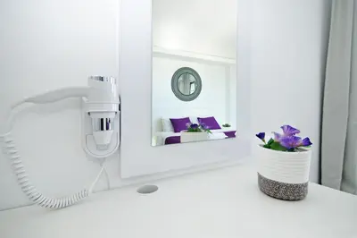 a white bathroom with a hair dryer and a mirror at Apartment Josephine - Beachfront in Protaras