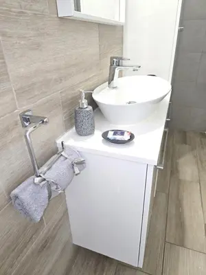 a white bathroom with a sink and a mirror at Seaside Escape Apartment in Larnaka