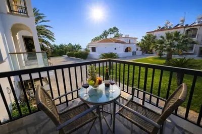a table with fruit and wine glasses on a balcony at Seaside Escape Apartment in Larnaka