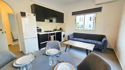 a living room with a dining table and a kitchen at La Magenta Apartments in Pyla
