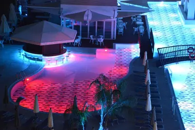 a pool with red lighting in a restaurant at night at Vassos Nissi Plage Hotel & Spa in Ayia Napa