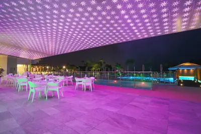 a restaurant with white tables and chairs and purple lights at Vassos Nissi Plage Hotel & Spa in Ayia Napa