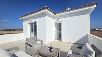 a white house with chairs and a patio at STAY Villa Harsha in Ayia Napa