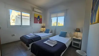 two beds in a room with two windows at STAY Villa Harsha in Ayia Napa