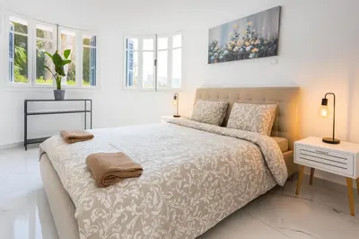 a white bedroom with a large bed and windows at Limassol Centr Apartament in Limassol