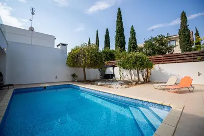 a swimming pool with two chairs next to a house at Beachfront Villa Larnaka Dhekelia with Pool in Pyla