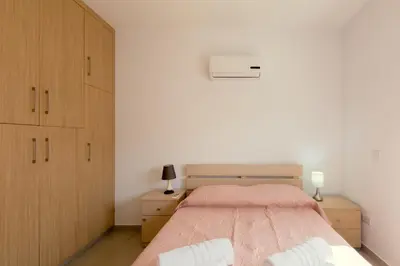 a bedroom with a bed and two wooden cabinets at Obv 2304 in Pyla