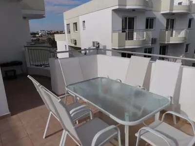 a balcony with a glass table and chairs at Oceania Bay Residence in Pyla