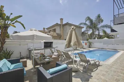 a pool with chairs and a table and an umbrella at Protaras Pearl Villa Pe15 in Protaras