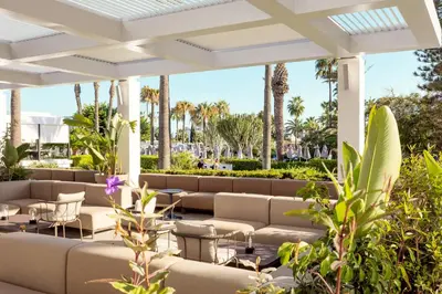a patio at the resort with couches and palm trees at SUNWING Sandy Bay Beach Village in Ayia Napa