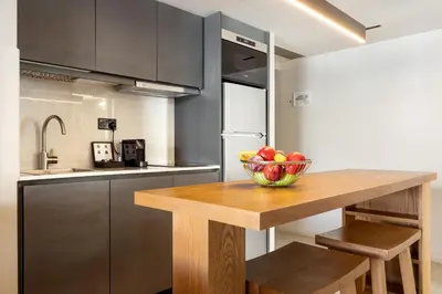 a kitchen with a wooden table with a bowl of fruit at SUNWING Sandy Bay Beach Village in Ayia Napa