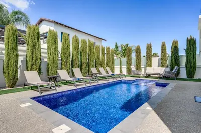 a pool with chairs and a table and a building at Serene Villa Retreat in Protaras in Paralimni