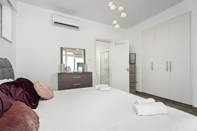 a white bedroom with a large bed and a mirror at Serene Villa Retreat in Protaras in Paralimni