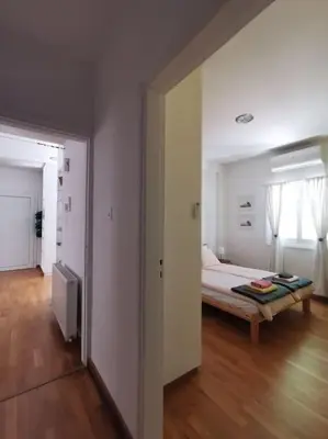 a white bedroom with a bed and a wooden floor at Cozy Family Home in Laxia