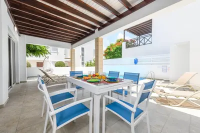 a dining room with a white table and blue chairs at Konnos Breeze Villa in Protaras