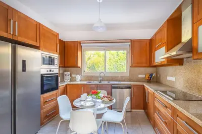 a kitchen with wooden cabinets and a table and chairs at Agios Tychon Luxury Villa with Private Pool in Limassol