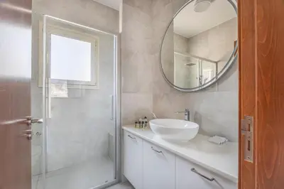 a bathroom with a sink and a shower with a mirror at Agios Tychon Luxury Villa with Private Pool in Limassol