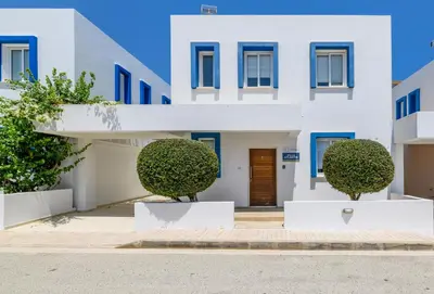 a white building with blue windows and bushes at Villa Atlantis in Protaras