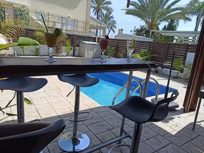 a table with drinks on it next to a swimming pool at Casa Palmera in Paralimni