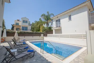 a swimming pool with chairs next to a building at Mylos Villas in Protaras
