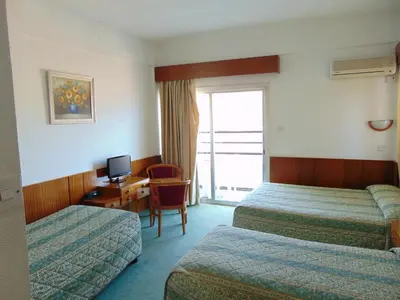 a hotel room with two beds and a desk with a computer at Hellas Hotel in Kakopetria