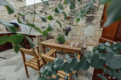 a wooden table and chairs in a stone wall at The Yard Traditional Residence in Vasa Kilaniou