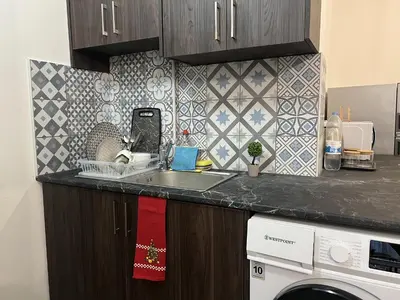 a kitchen counter with a sink and a washing machine at 1 room apartment on the 1st line in Limassol