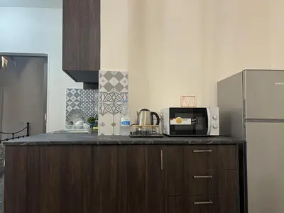 a kitchen with a counter with a microwave and a refrigerator at 1 room apartment on the 1st line in Limassol