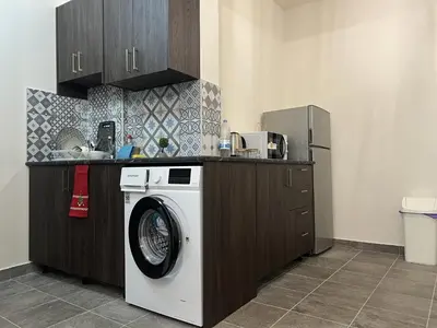 a kitchen with a washing machine under a counter at 1 room apartment on the 1st line in Limassol