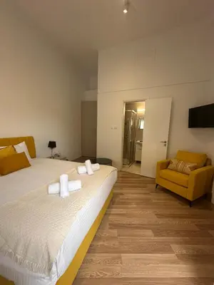 a bedroom with a large bed and a yellow chair at Joanna's Rooms in Kalopanayiotis