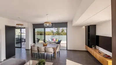 a dining room and living room with a table and chairs at Villa Iva by the Sea in Paralimni