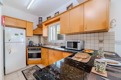 a kitchen with wooden cabinets and a white refrigerator at Villa Kos #7 in Paralimni