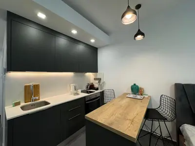 a kitchen with black cabinets and a wooden table at Courtyard Holiday Resort Studio in Iskele
