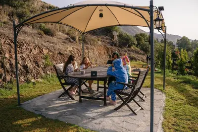a group of people sitting at a table under an umbrella at Cozy Glamping Cabin for Couples and Families in Arakapas