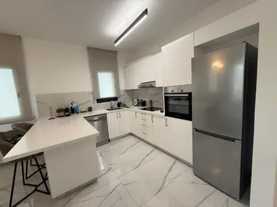a kitchen with white cabinets and a stainless steel refrigerator at Glabur Stays - Nicosia's Finest 2 Bedroom in Nicosia