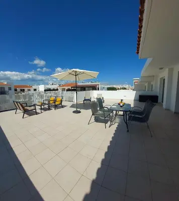 a patio with chairs and a table and an umbrella at Tide Terrace 2 bdr apt in Kapparis, Protaras in Paralimni