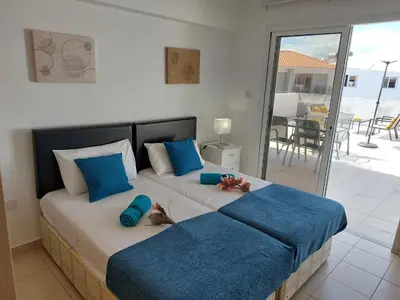 a bedroom with two beds with blue pillows and a balcony at Tide Terrace 2 bdr apt in Kapparis, Protaras in Paralimni
