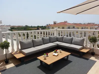 a couch and a table on a balcony at Nissi Retreat - Walk to Nissi beach! in Ayia Napa